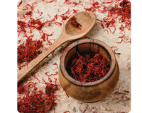 Vibrant red saffron threads freshly harvested, laid out with a wooden spoon, showcasing the delicate and prized part of the saffron crocus flower.